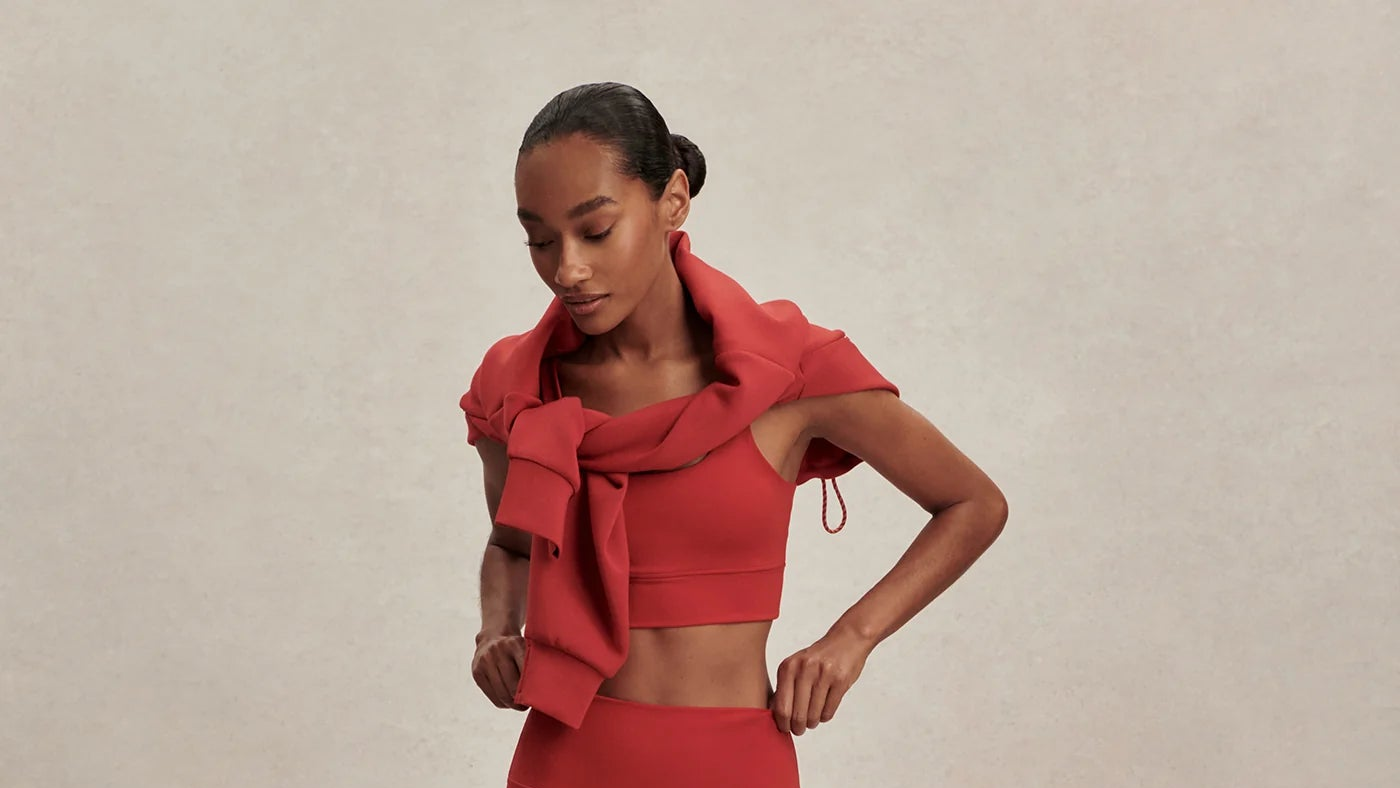 Woman wearing a red outfit with a matching scarf against a beige background