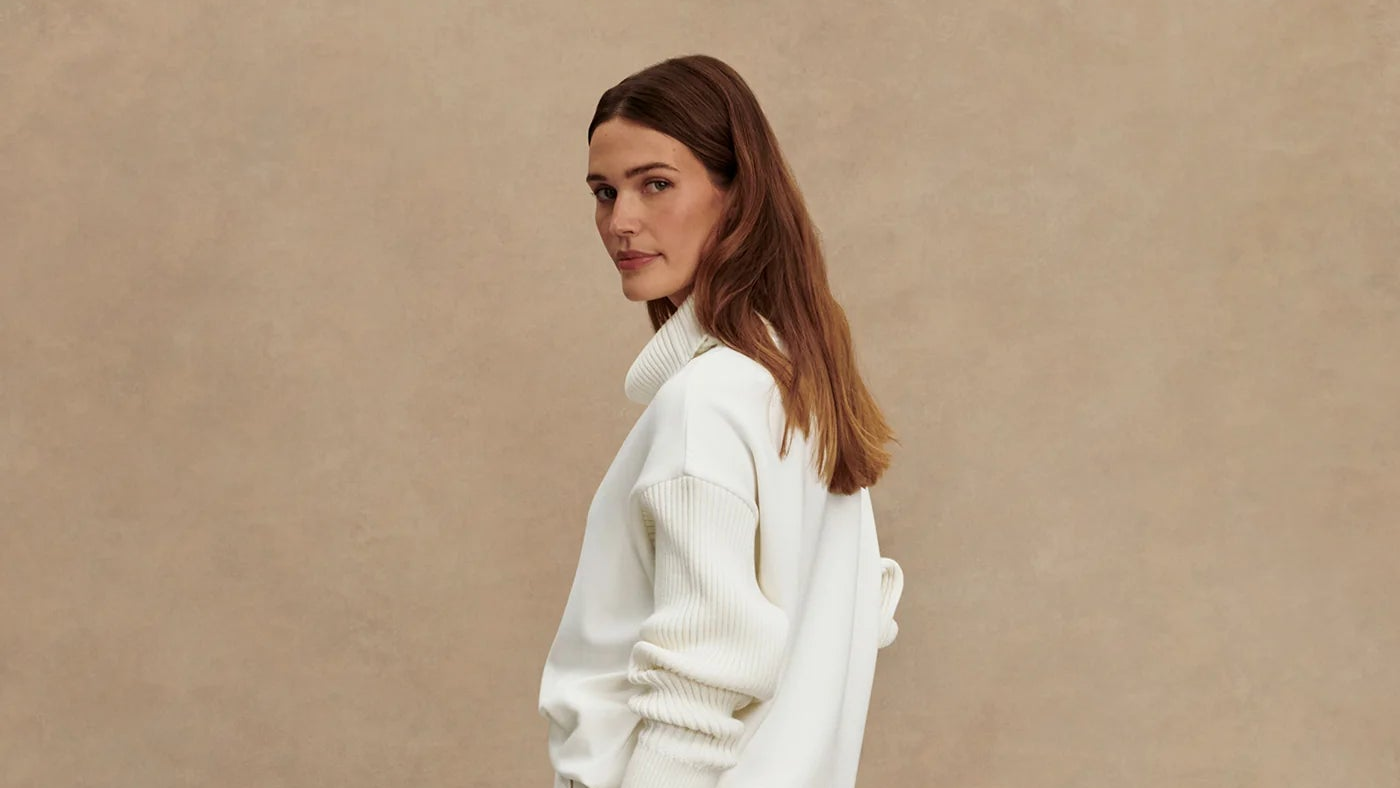 Woman wearing a white sweater against a beige background